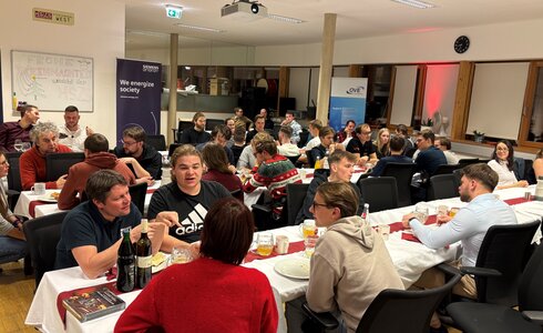 Eine Gruppe von Menschen sitzt an Tischen und genießt ein gemeinsames Essen.