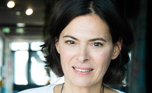 Porträt einer Frau mit kurzen Haaren, die freundlich in die Kamera lächelt.