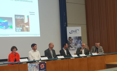 Podiumsdiskussion über Quantenmechanik mit mehreren Experten auf der Bühne.