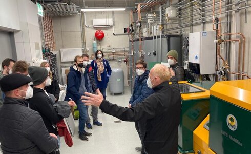 Gruppe von Menschen hört einem Referenten in einer technischen Anlage zu.