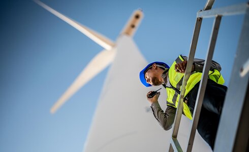 Ein Arbeiter spricht über Funkgerät an einer Windkraftanlage.