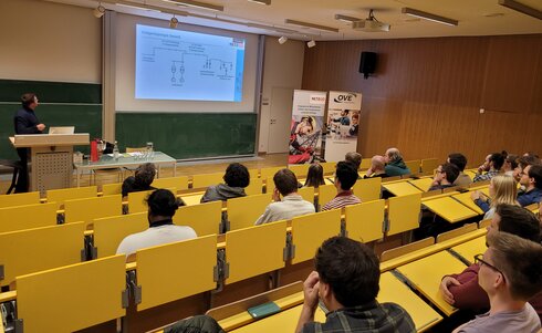 Ein Referent präsentiert vor einer Zuhörerschaft in einem Hörsaal.