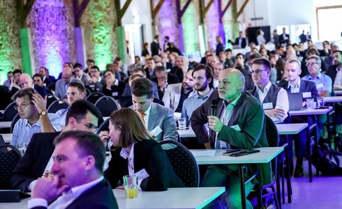 Konferenz mit vielen Teilnehmern, die einem Referenten aufmerksam zuhören.