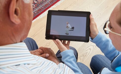 Älterer Mann und Frau schauen gemeinsam auf ein Tablet.