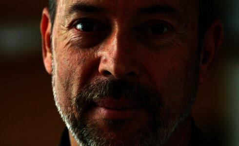 Ein Mann mit Bart und grauem Haar lächelt in die Kamera.