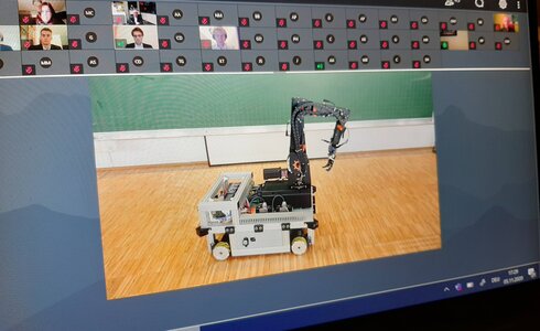 Ein Modellroboter mit einem Kranarm auf einem Holzboden.