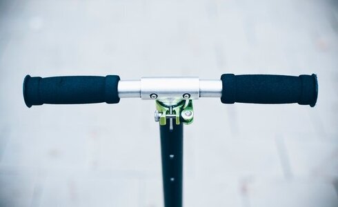 Griff eines Tretrollers mit schwarzen Handgriffen und silbernem Lenker.