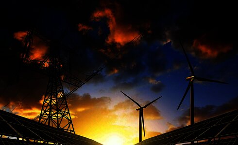 Nachhaltige Energieerzeugung mit Windkraft, Solarpanelen und Hochspannungsleitung bei Sonnenuntergang.