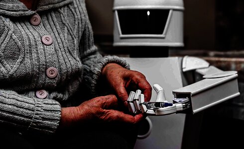 Eine ältere Person hält einen Spritzenbehälter in der Hand.