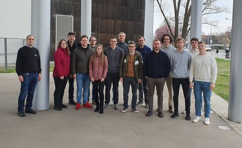 Gruppe von Menschen posiert im Freien vor einem modernen Gebäude.