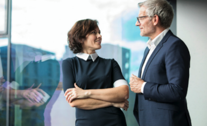 Zwei Personen führen ein Gespräch in einem modernen Büro mit Fensterblick.