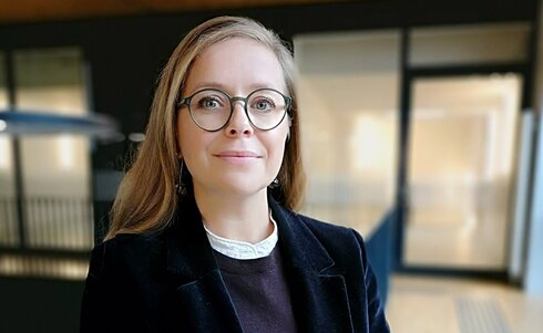 Eine Frau mit Brille trägt einen schwarzen Blazer und lächelt freundlich.