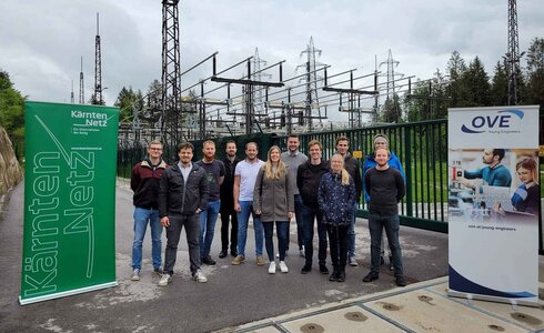 Gruppenfoto von Menschen vor einem Kraftwerksgelände mit Bannern von Kärnten Netz und OVE.