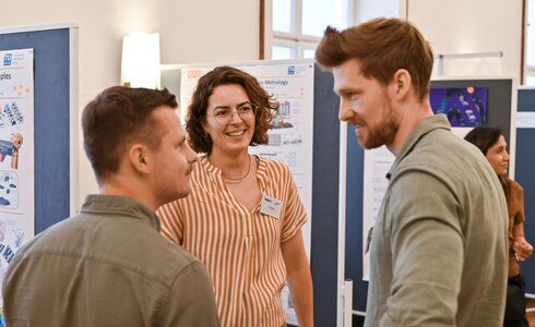 Drei Personen in einem Gespräch auf einer Veranstaltung.