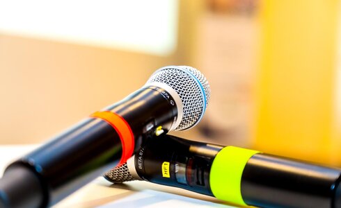 Zwei Mikrofone mit orangefarbenem und grünem Ring liegen nebeneinander.