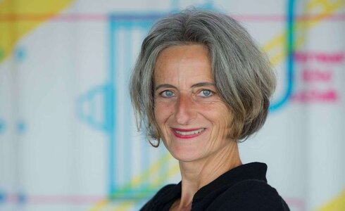 Porträt einer lächelnden Frau mit grauen Haaren und blauen Augen.