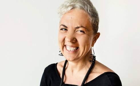 Eine lächelnde Frau mit kurzen, grauen Haaren und Ohrringen.