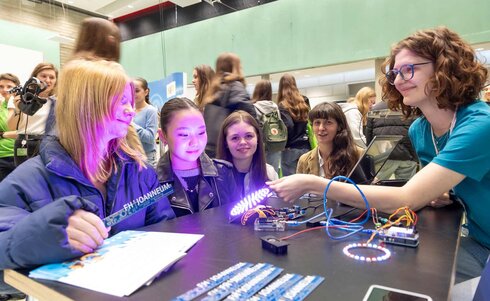 Mädchen experimentieren mit Elektronik und LED-Lichtern auf einer Veranstaltung.