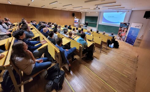 Ein Vortragssaal mit vielen Zuhörern, die auf eine Präsentation schauen.