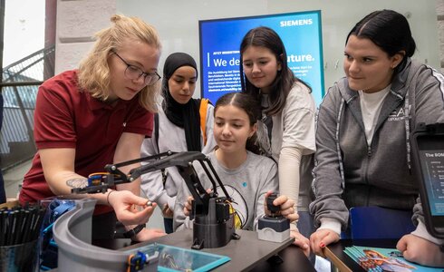 Eine Person zeigt vier Jugendlichen ein technisches Gerät.