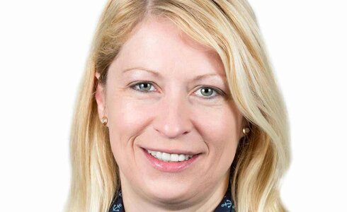 Ein Portrait einer lächelnden Frau mit blonden Haaren und einem blauen Schal.