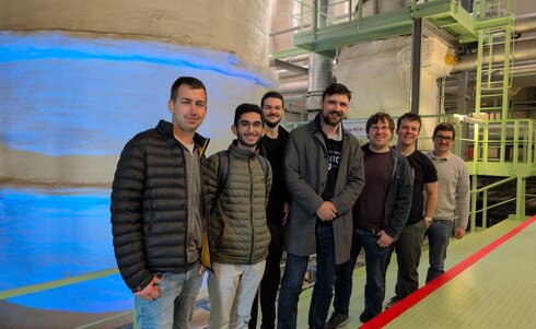 Eine Gruppe von sieben Personen steht in einer industriellen Umgebung.