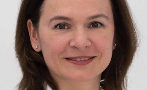 Porträt einer Frau mit schulterlangen, braunen Haaren, die freundlich lächelt.