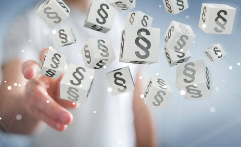 Eine Hand greift nach schwebenden Würfeln mit Paragraphensymbolen.