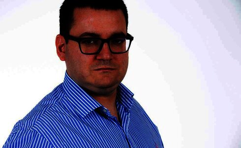 Ein Mann mit Brille und gestreiftem Hemd blickt ernst in die Kamera.