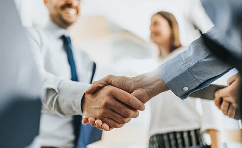 Händedruck zwischen zwei Personen in einem geschäftlichen Kontext.