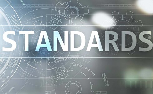 Der Text "STANDARDS" vor einem technischen Hintergrund mit Zahnrädern und Diagrammen.