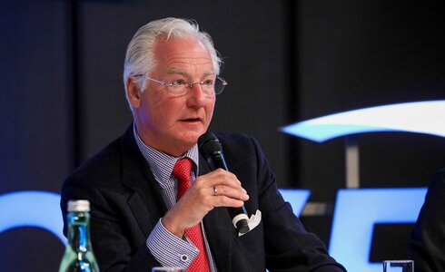 Ein Mann spricht mit einem Mikrofon während einer Diskussion auf einer Veranstaltung.