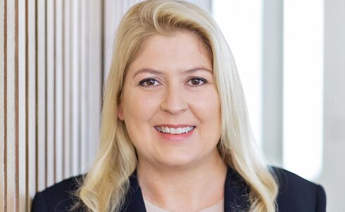 Portrait einer lächelnden Frau mit blonden Haaren in einem blauen Blazer.