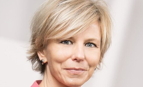 Porträt einer Frau mit blonden, kurzen Haaren und freundlichem Gesichtsausdruck.