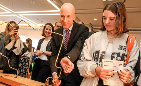 Eine Person testet ein Experiment, während andere Zuschauer interessiert zuschauen.