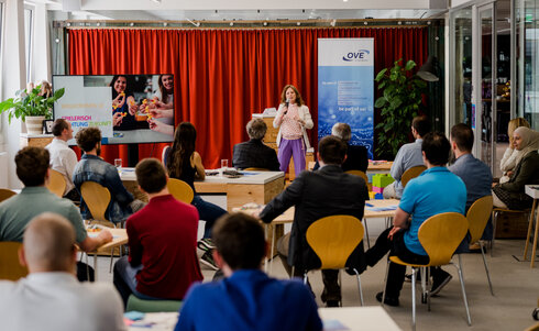 Eine Frau präsentiert vor einem Publikum in einem Seminarraum.