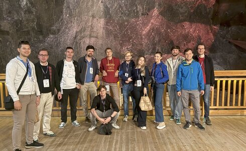 Gruppe von 15 Personen auf einer Holzplattform in einer Bergwerk-Umgebung.