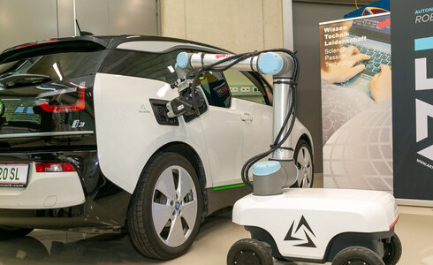 Ein Elektrowagen wird von einem Roboterarm aufgeladen.