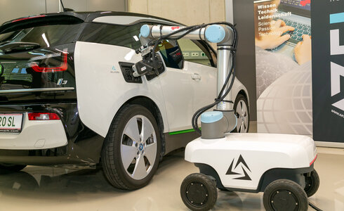 Ein Elektrowagen wird von einem Roboterarm aufgeladen.