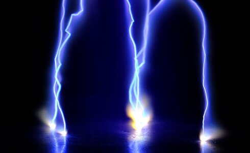 Blaues Licht des Blitzes, der über dunklem Hintergrund zu sehen ist.