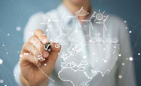 Eine Hand zeichnet eine nachhaltige Welt mit Energiequellen und Natur.