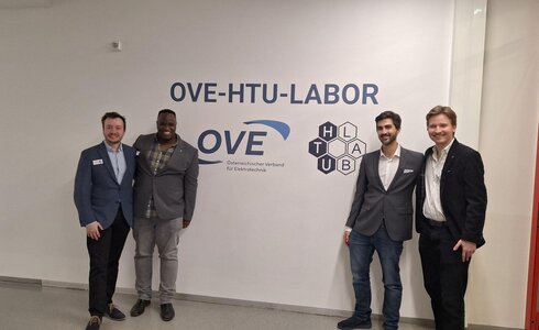 Vier Personen posieren vor dem OVE-HTU-Labor-Schild.