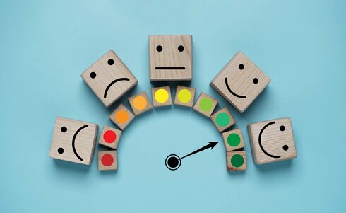 Fünf Holzklötze mit verschiedenen Gesichtsausdrücken in einem Halbkreis angeordnet.